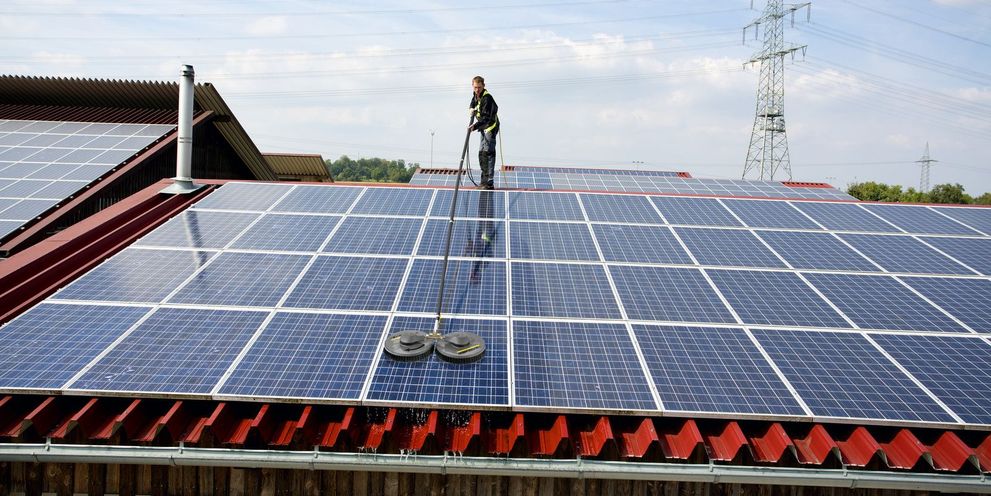 A person cleans a solar system on a roof