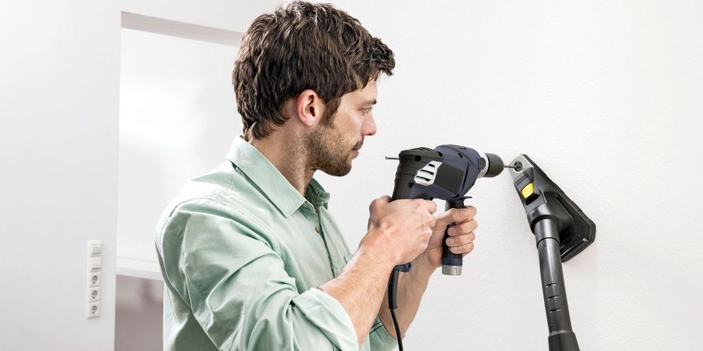 A man drills with the help of a Kärcher drill dust catcher