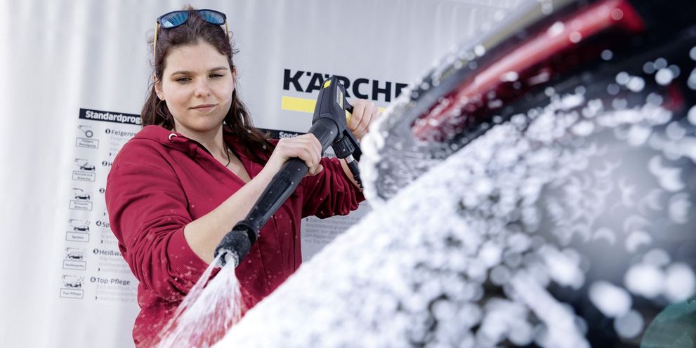 A woman lathers her car with a Kärcher changeover lance