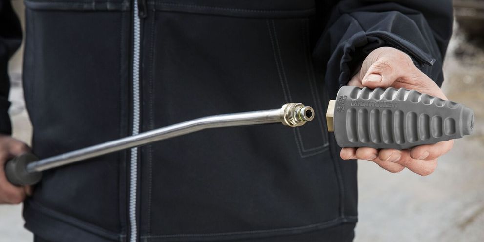 A person screws a nozzle onto a high-pressure cleaner