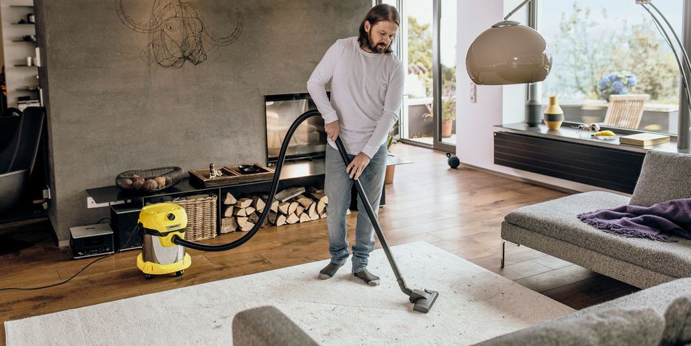 Person vacuums in living room Wet and dry vacuum cleaners for inside areas