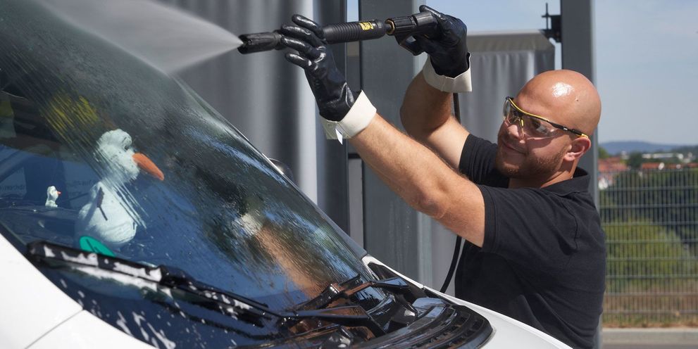 A man cleans the windshield of his caravan with a Kärcher pressure washer