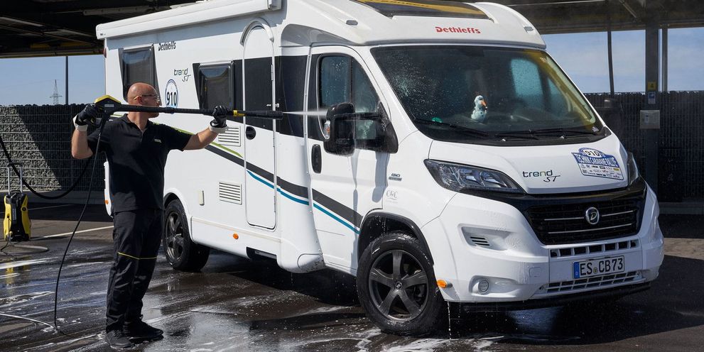 A man cleans the windows of the with a Kärcher pressure washer