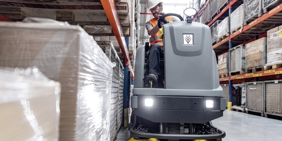 A man cleans the floor with a Kärcher ride-on sweeper