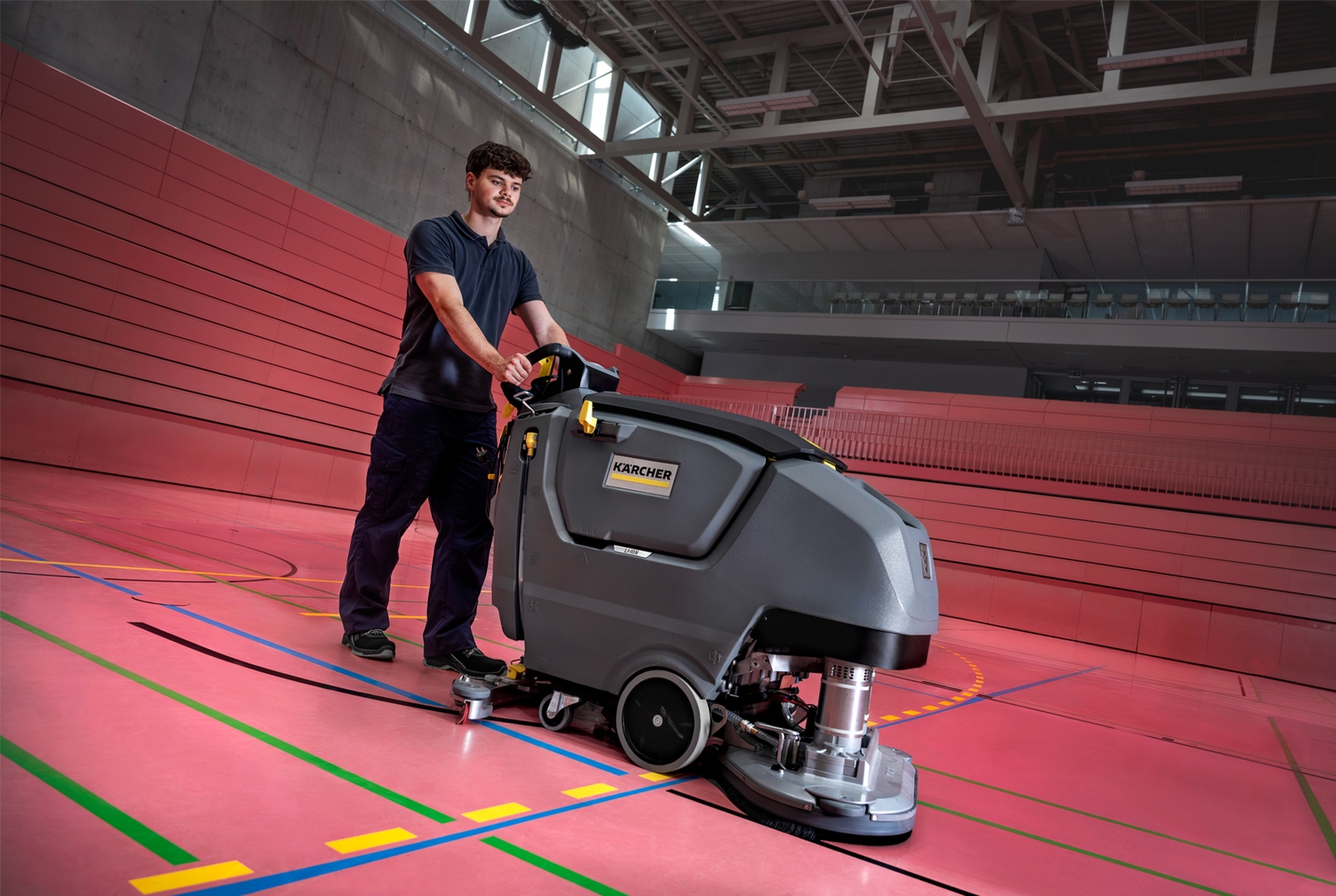 man achter schrobmachine in sportzaal 