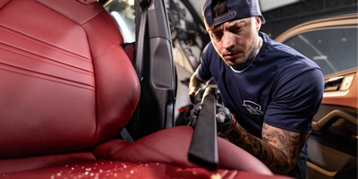 man die met stofzuiger auto aan het uitzuigen is