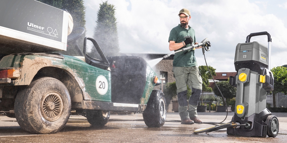 man die golfkar aan het schoonspuiten is