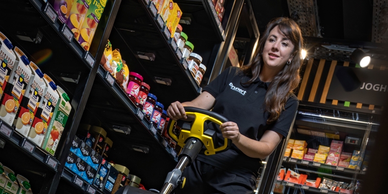 vrouw achter schrobber in een supermarkt
