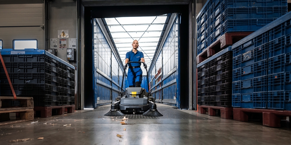 vrouw die met veegmachine hal aan het reinigen is