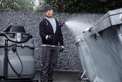 Person cleaning a trash bin