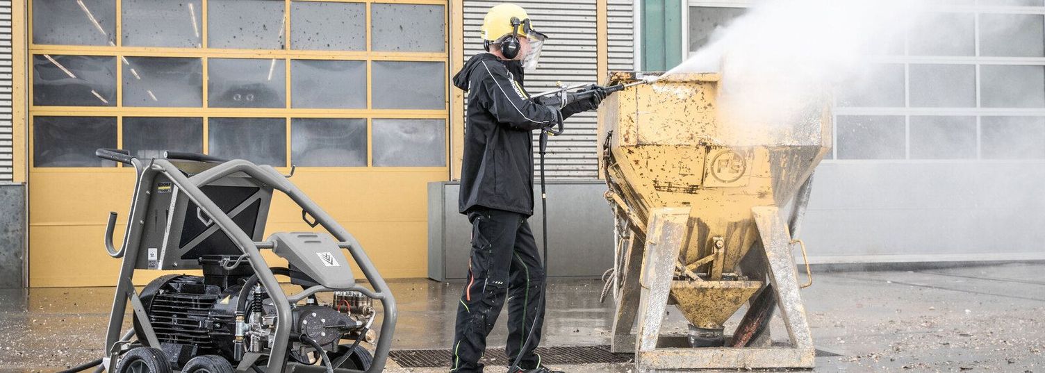 A person wearing protective clothing cleans scaffolding with a Kärcher Ultra-High-Pressure Cleaner