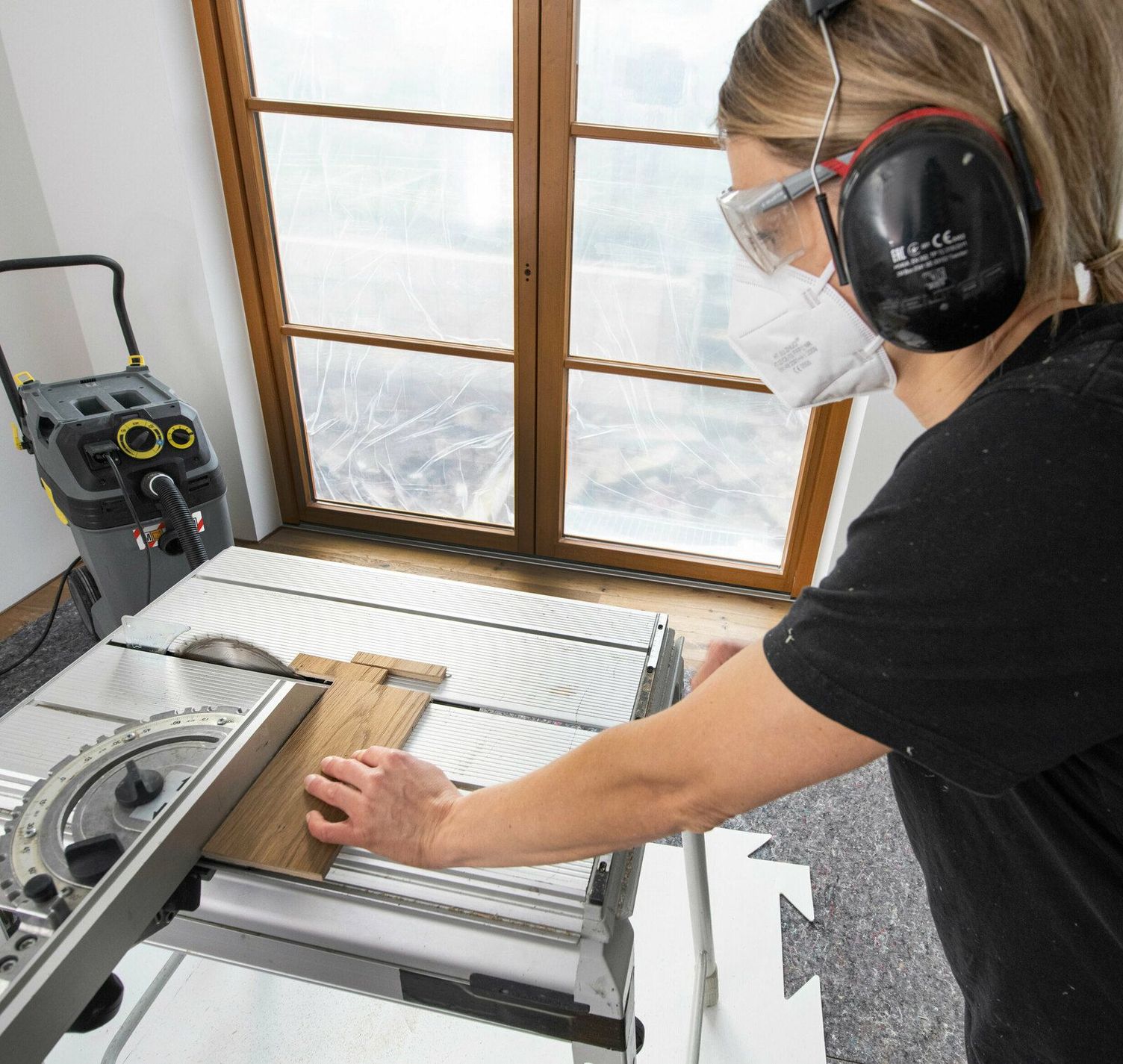 One person saws wood at a machine