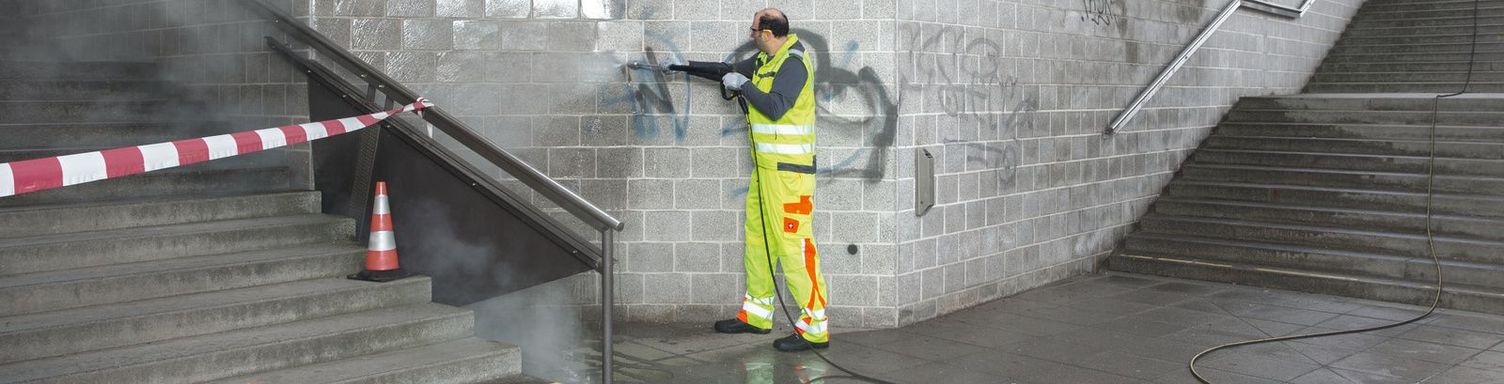 A person removes graffiti from an underpass with the help of a Kärcher high-pressure cleaner.