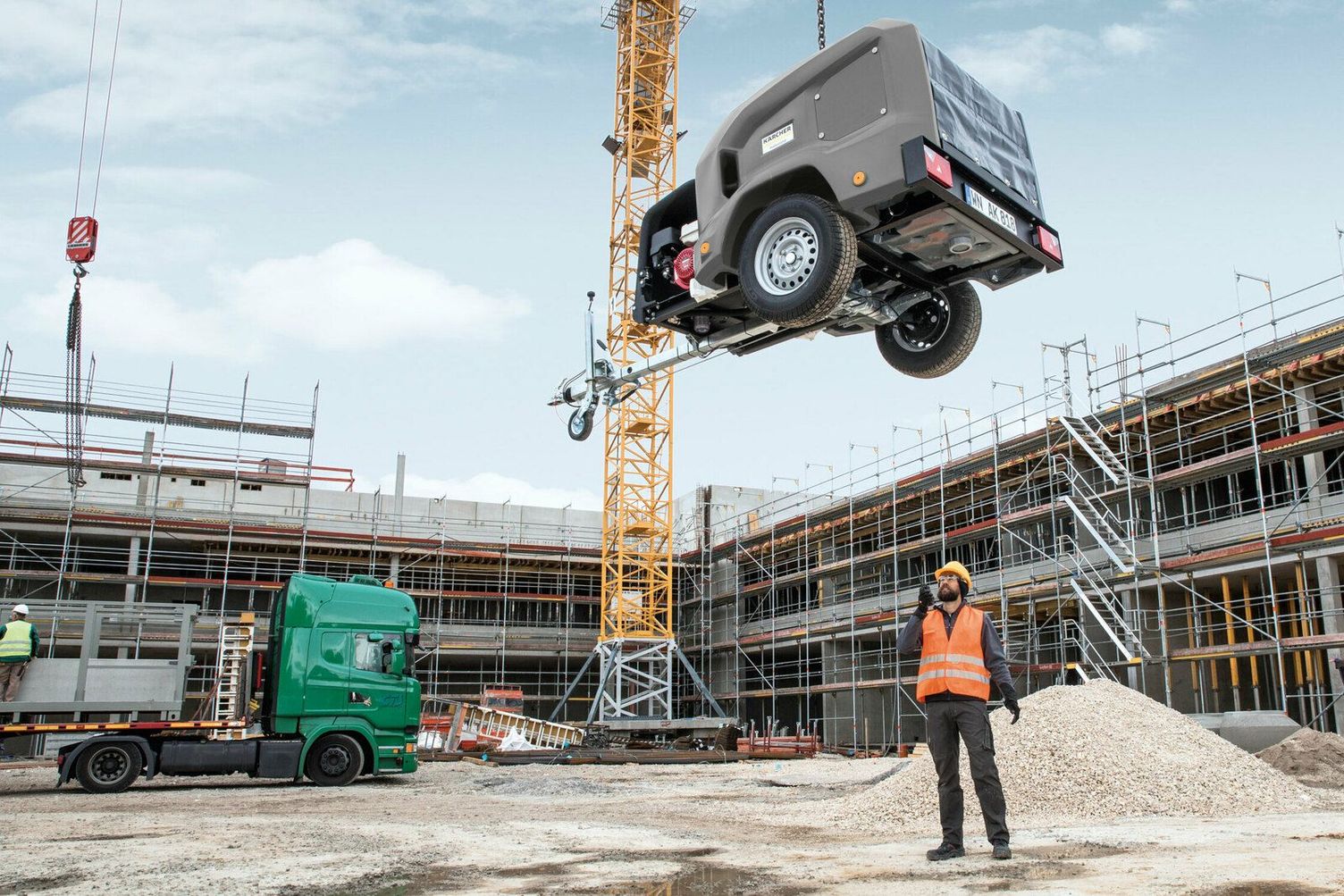A person coordinates the lowering of an HDS trailer with a crane hook 