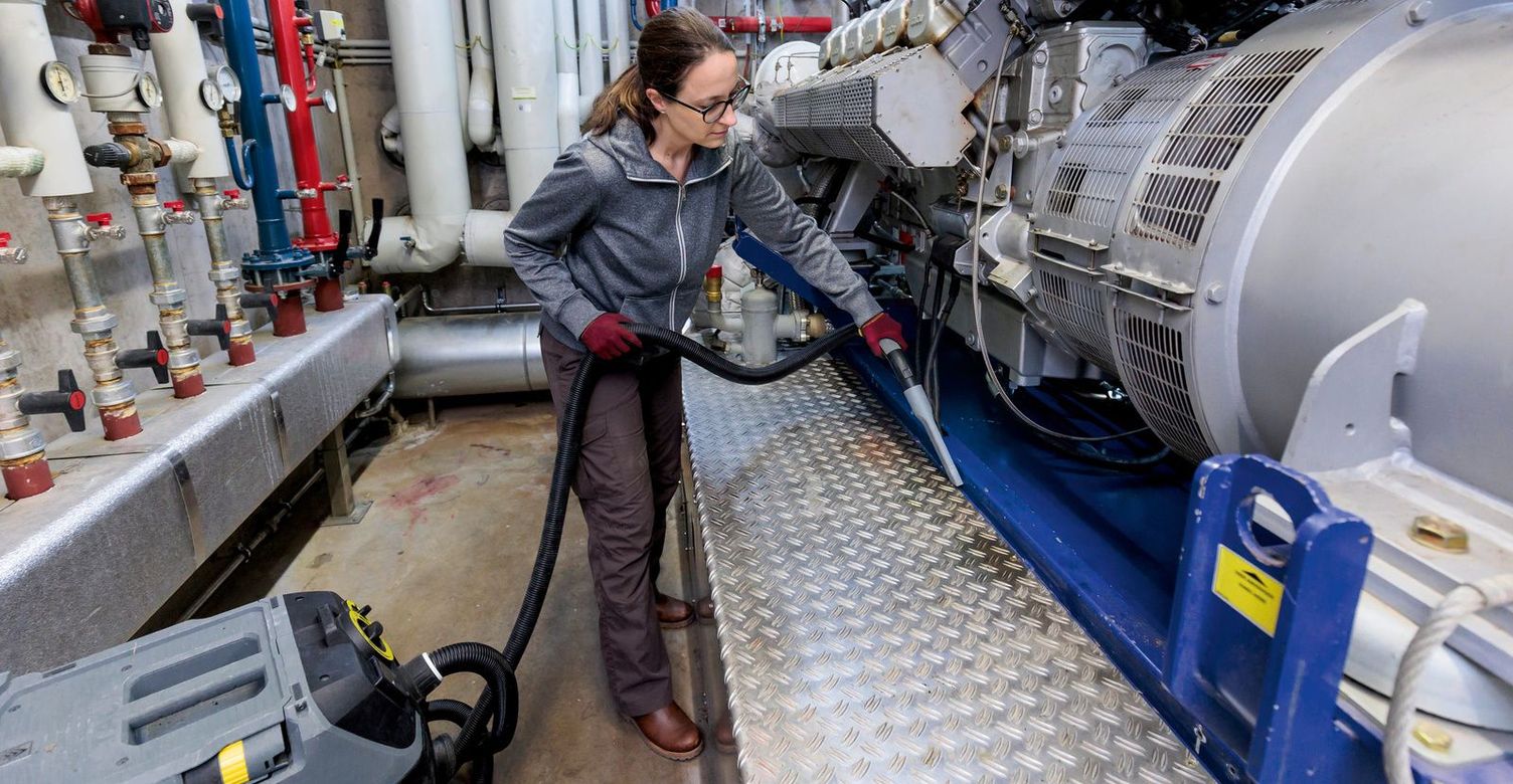 A woman uses a Kärcher wet and dry vacuum cleaner in the generator room