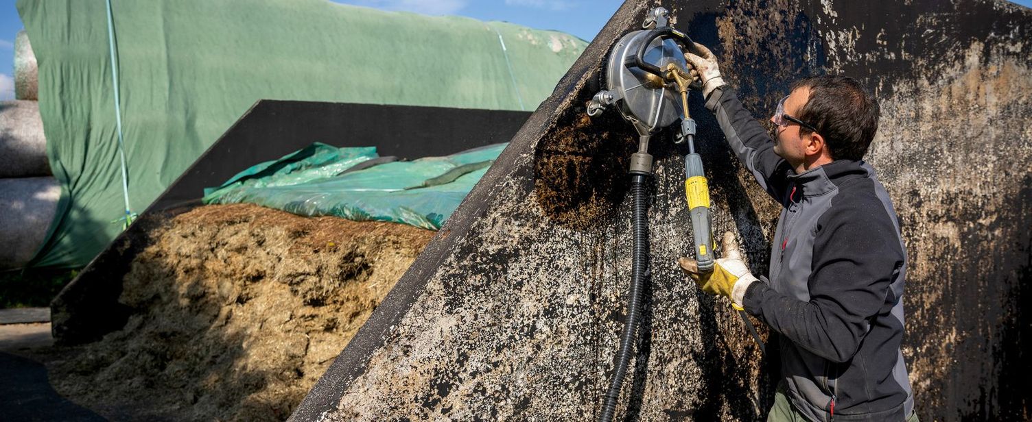 A man cleans a silo with a Kärcher surface cleaner