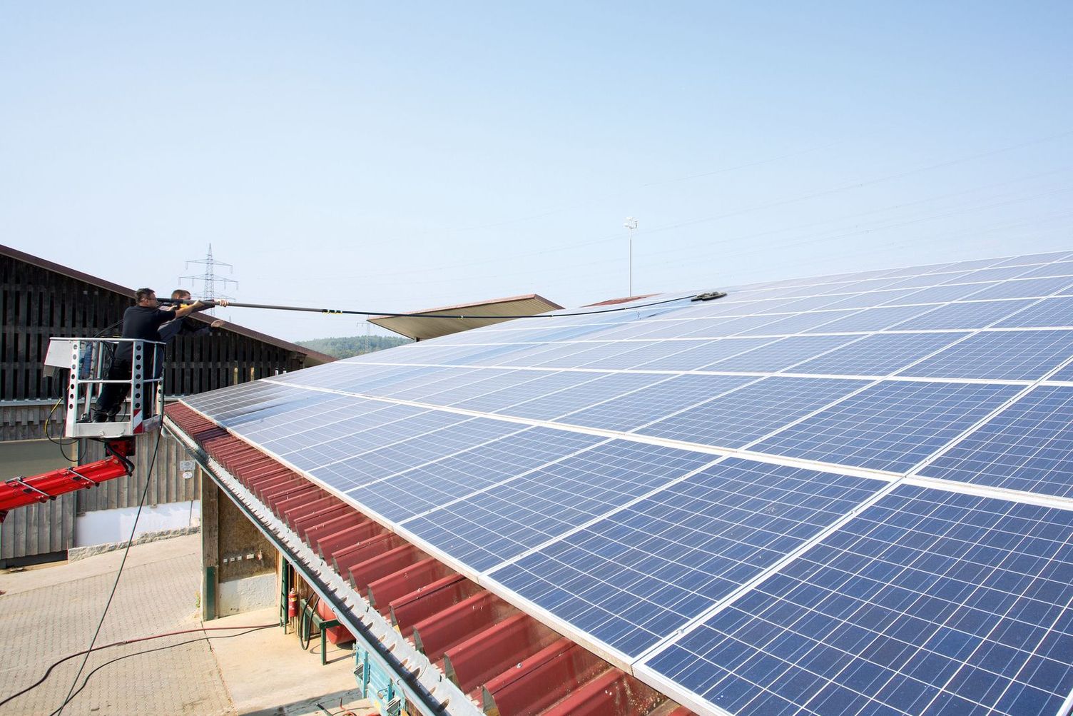 Cleaning photovoltaic panels with a cherry picker
