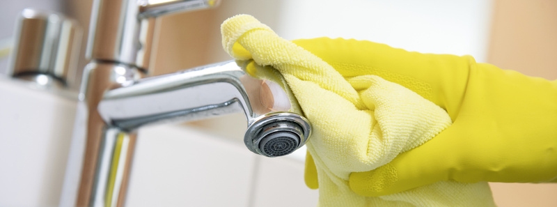 A sink including tap being cleaned with a microfiber cloth