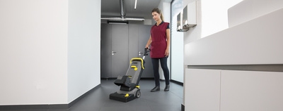 A person cleaning the floor in the toilet area