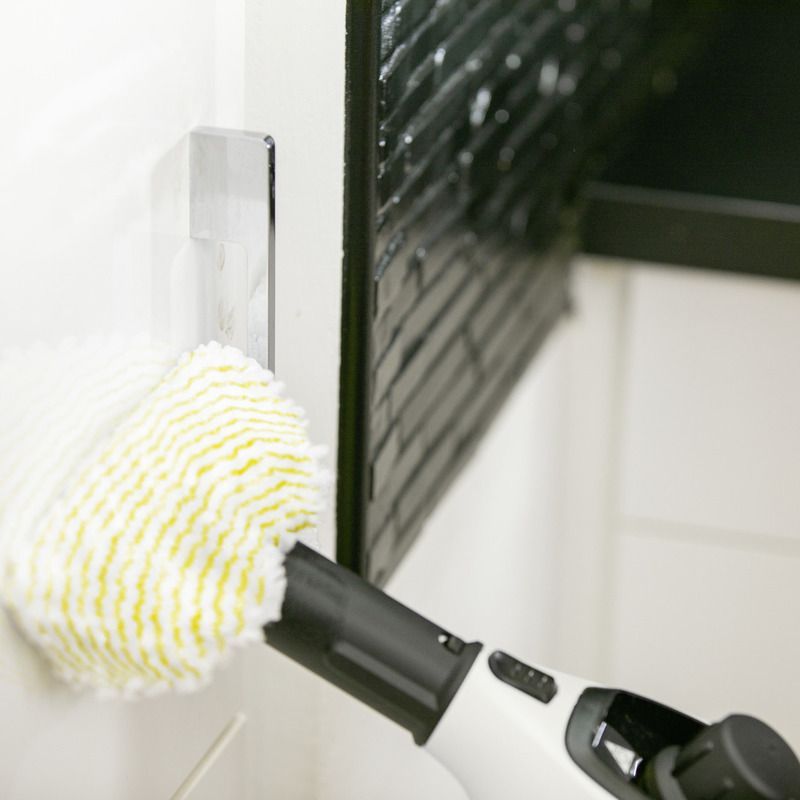 Person cleaning wall using Kärcher steam cleaner SC 1 EasyFix