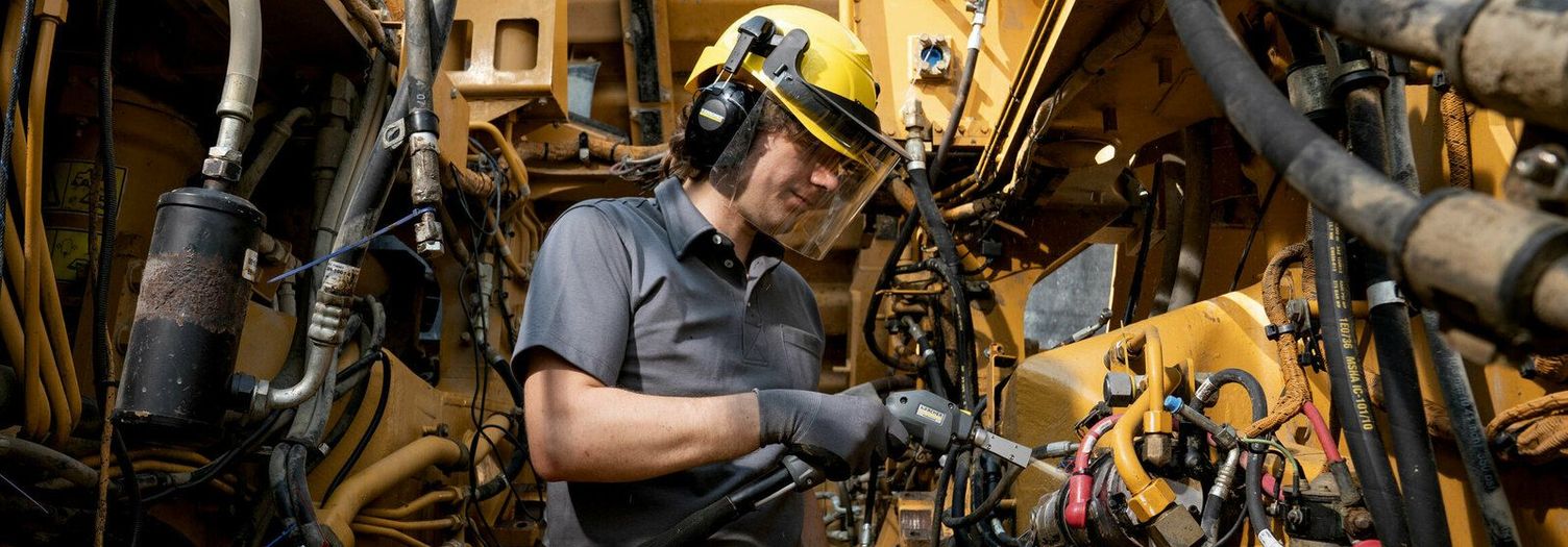 A person cleans the interior of a construction machine with a Kärcher Dry Ice Blaster