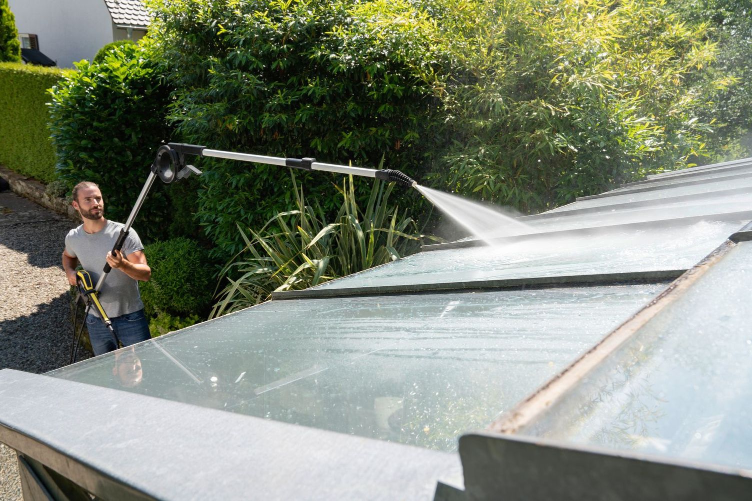 A man cleans a conservatory with the help of a Kärcher telescopic jet pipe