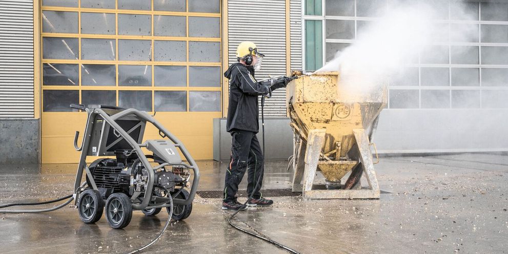 A person in protective clothing cleans shuttering with a Kärcher Ultra-High-Pressure Cleaner