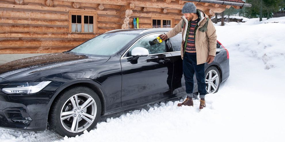 Man de-icing his car in snow