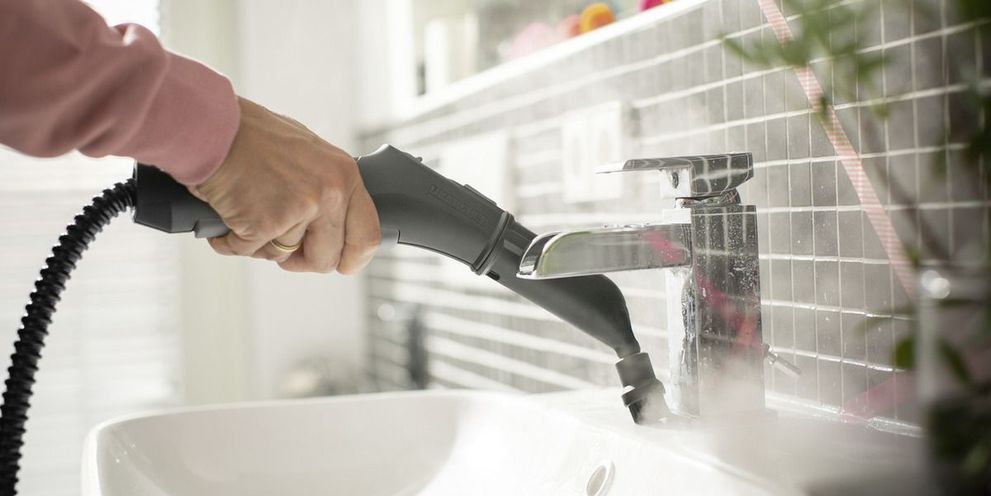 Person cleaning bathroom using Kärcher steam cleaner