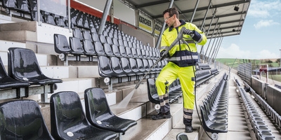 Person cleaning a soccer stadium with a high pressure cleaner