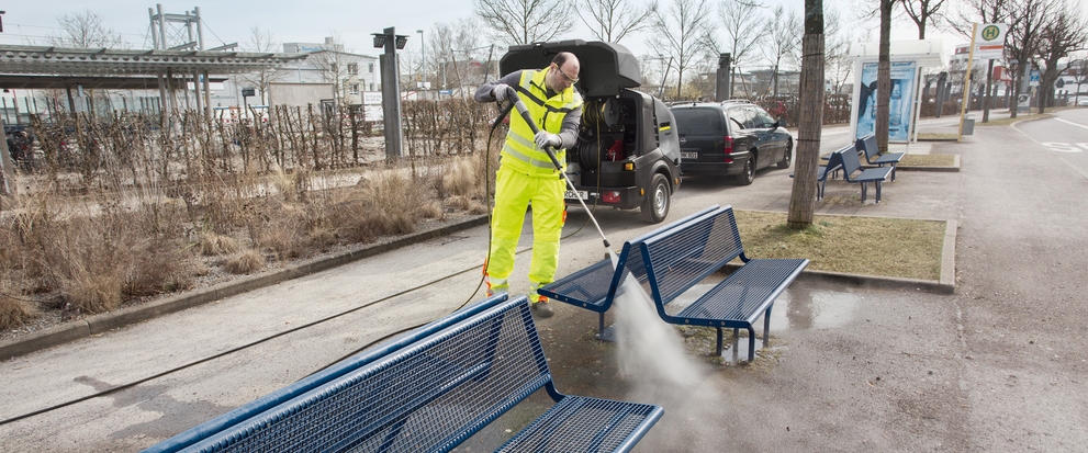 Person cleaning a park bench with a HDS high pressure cleaner
