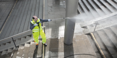 Person cleaning a train station with a Hogh pressure washer