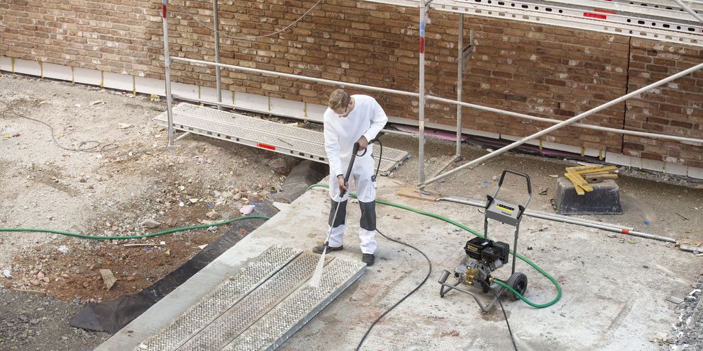 A man cleans a scaffold floor using a Kärcher High-Pressure Cleaner