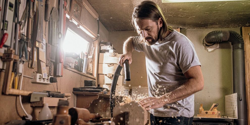 A man vacuums his DIY bench with a Kärcher wet and dry vacuum cleaner