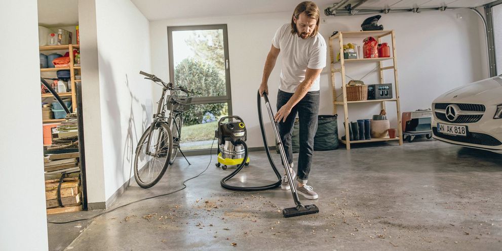 A man vacuums the garage floor with a Kärcher vacuum cleaner