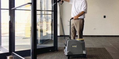 Person disinfecting a revolving door with a Kärcher spray system