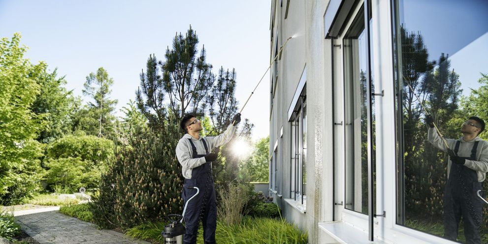 A man cleaning a plaster facade with a Kärcher high-pressure cleaner.