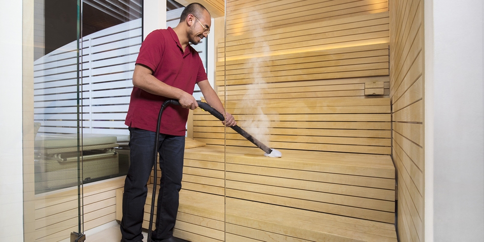 Person cleaning a saune with a Kärcher steam cleaner