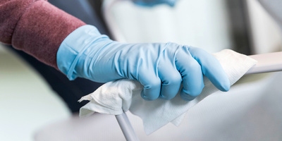 Wiping a chair with a single use disinfectant cloth