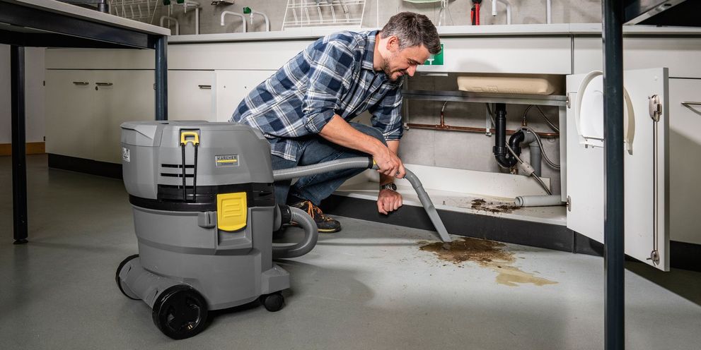 A person removes dirt with a Kärcher Battery Wet and Dry Vacuum Cleaner