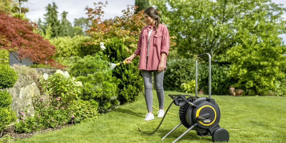 Un bărbat udă florile în grădină