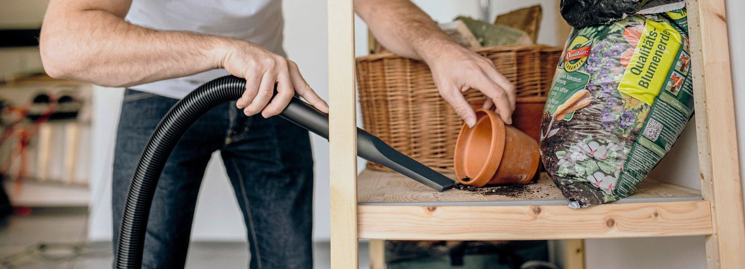 A man cleans a shelf in his garage with a Kärcher vacuum cleaner