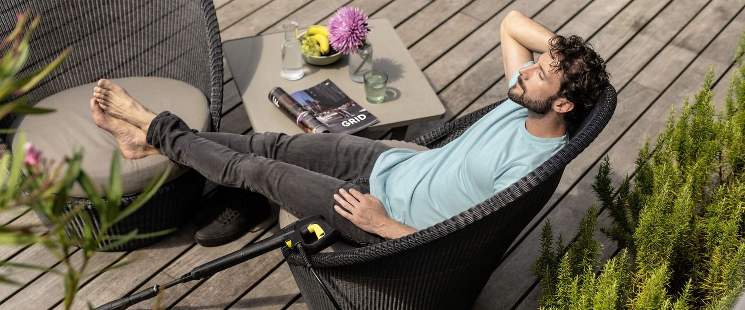 Man sitting on a terrace with Kärcher pressure washer beside him
