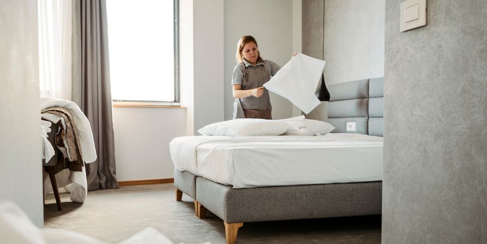 Making beds in the hotel room A woman tends to the hotel bed
