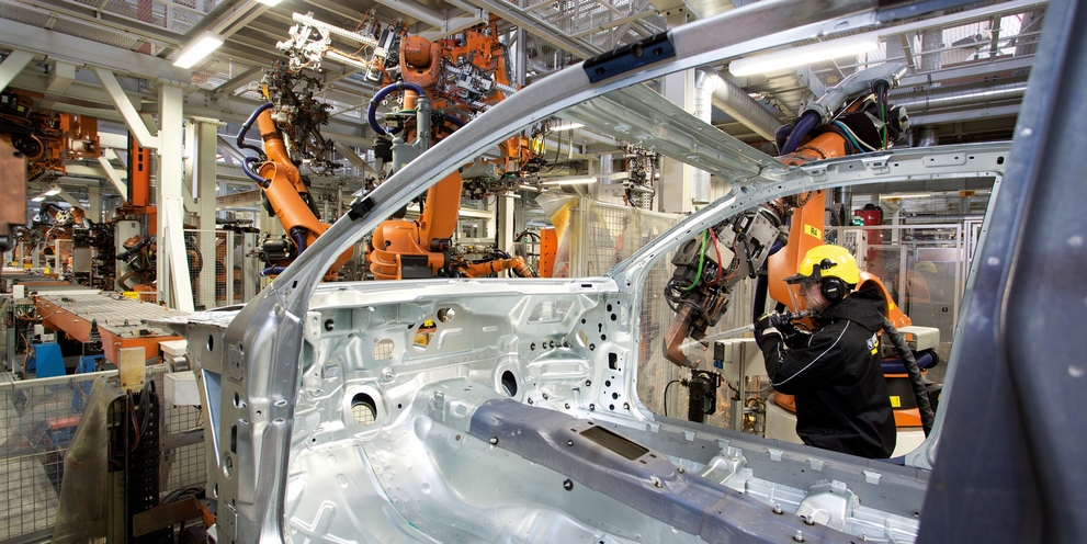 Employee cleans robot arm in automotive factory Employee cleans robot arm in automotive factory