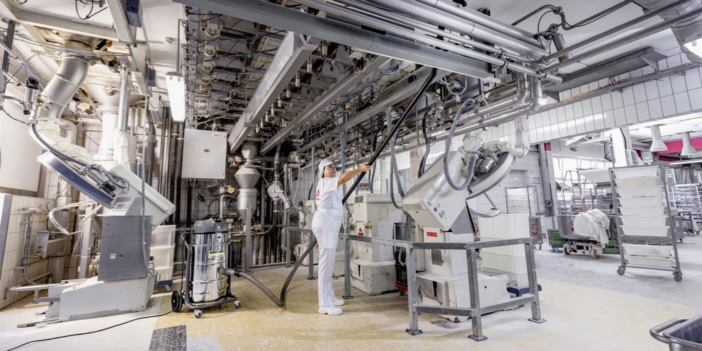 Worker cleans in bakery with vacuum cleaner Worker cleans in bakery with vacuum cleaner