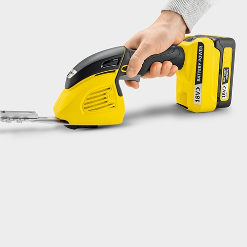 Person pressing the safety lock at the grass and shrub shear