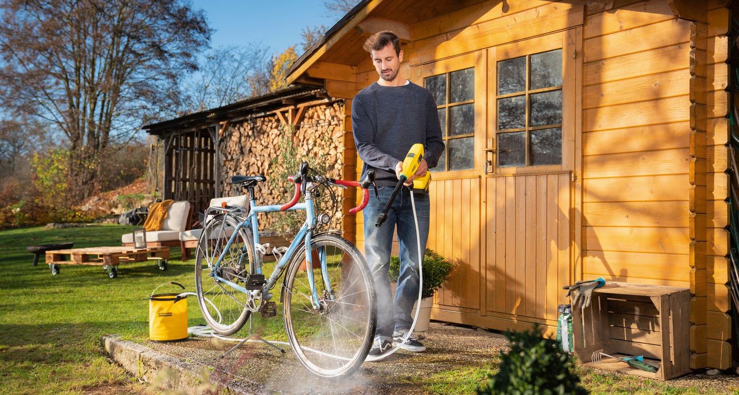A man cleans his road bike with a Kärcher handheld cleaner