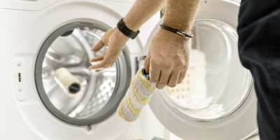 Person putting a floor cleaner roller in the washing machine