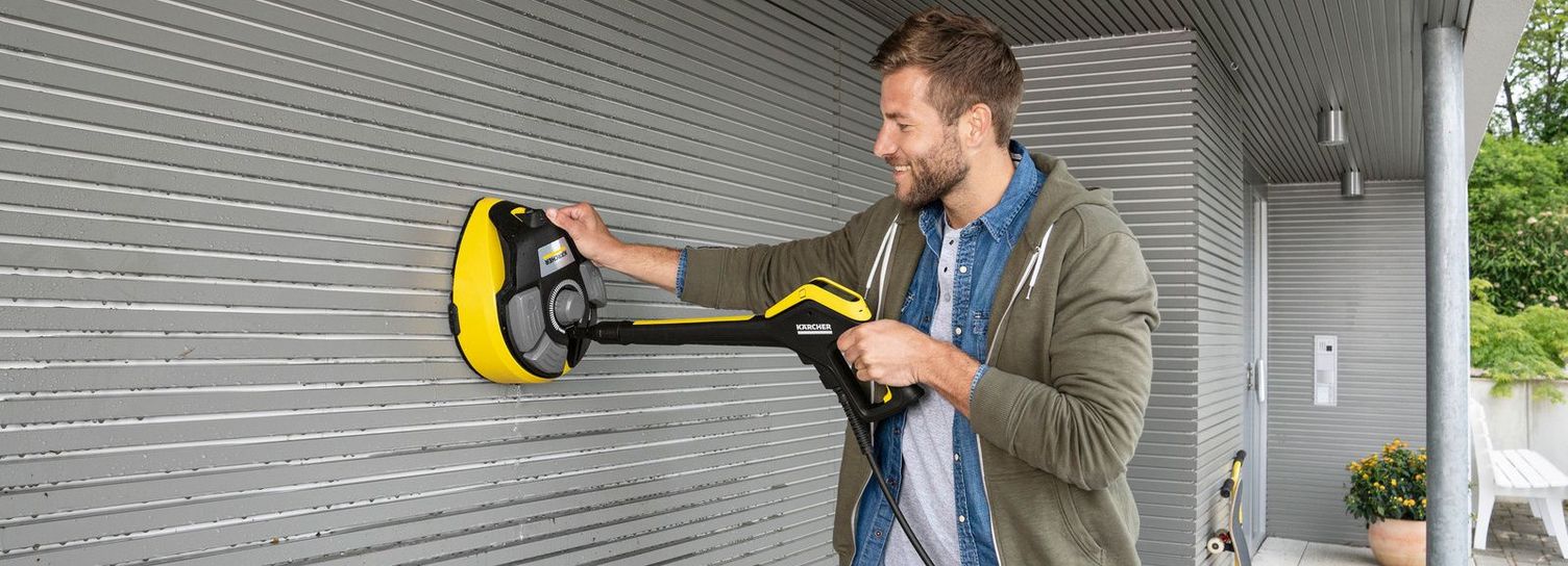 Cleaning the garage door A man cleans the garage door with a Kärcher medium pressure washer using the attachment for surfaces